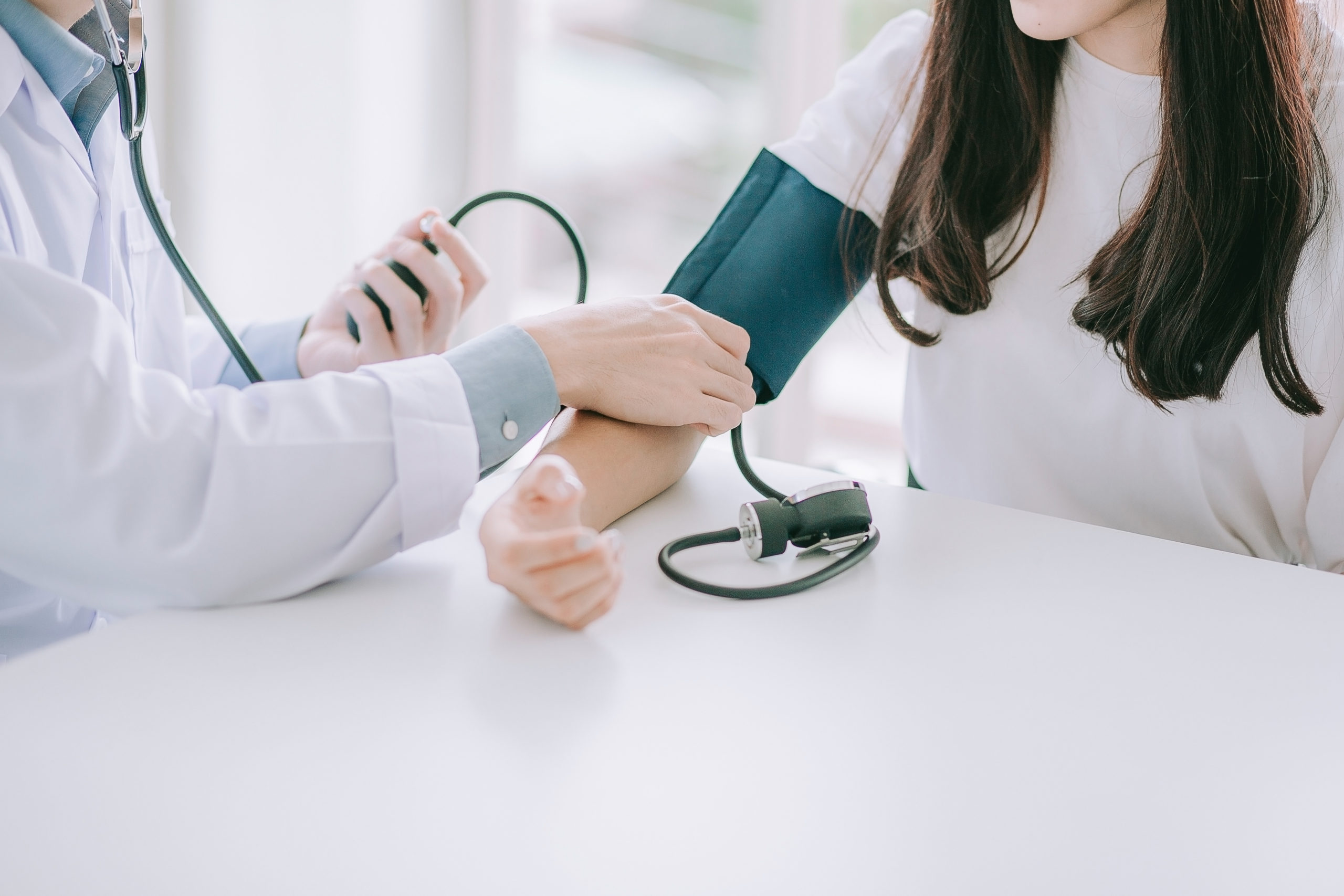 Doctor using sphygmomanometer with stethoscope checking blood pressure to a patient in the hospital.