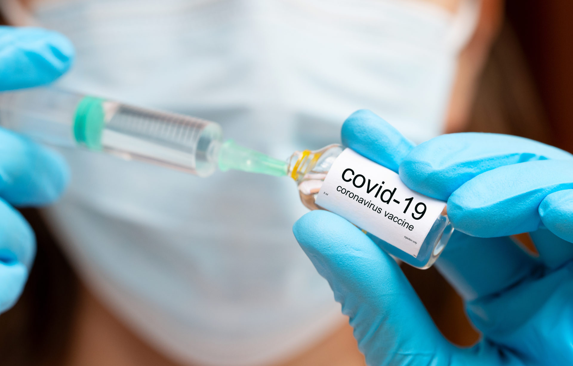 Making covid 16 vaccine injection, hands in medical gloves with vaccine ampoula and syringe